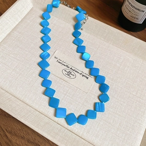 Detailed view of blue diamond-shaped shell beaded necklace on jewelry display tray