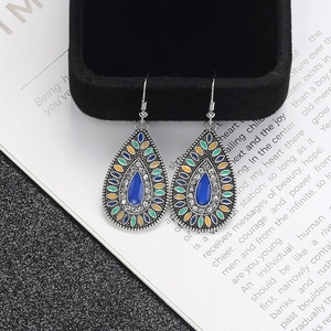 Detail of vintage silver boho teardrop earrings with colorful enamel on a book