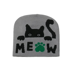 Detail of grey knitted beanie featuring black cat jacquard and green paw print with MEOW text
