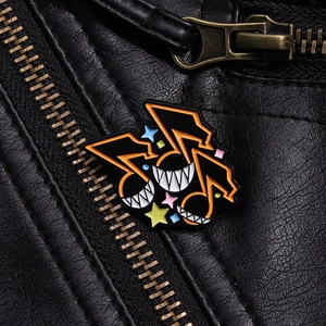 Gros plan détaillé d'un pin's émaillé orange en forme de note sur une veste en cuir