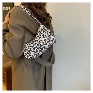 Détail du sac porté épaule à motif zèbre tendance porté par un mannequin sur fond de mur