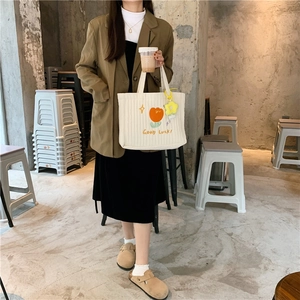 Detail of white quilted tote bag with orange tulip embroidery and lucky charm