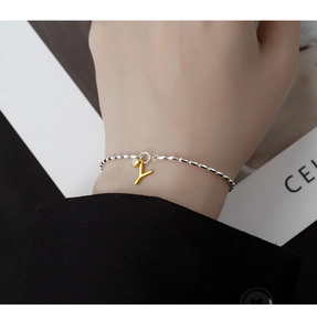 Detailed shot of an S925 silver beaded bracelet featuring a gold letter Y charm with zircon