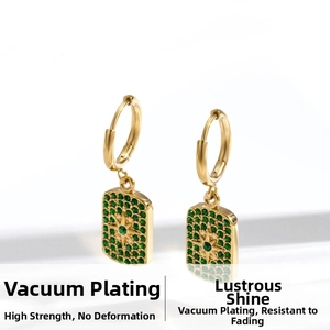 Detail view of gold earrings with square green zircon pendants and star motifs