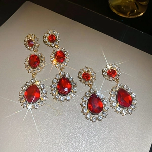 Détail macro de boucles d'oreilles vintage fleurs dorées avec gouttes de cristal rouge
