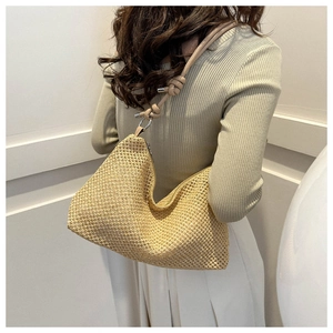Detailed back view of a beige hand-woven straw tote bag with knotted leather strap