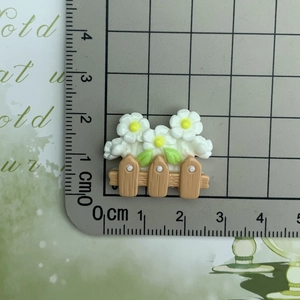 Close-up of small resin white flower on a brown fence measured with a ruler