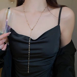 Detailed view of a gold-toned Y-shaped tassel necklace with heart and geometric charms
