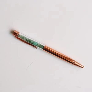 Detailed view of rose gold crystal pen with green aventurine stones in transparent barrel