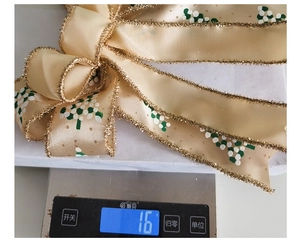Weight measurement of a champagne gold double-layered Christmas bow showing 16g on scale