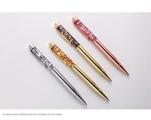 Close-up of four glitter liquid sand ballpoint pens in silver gold and rose gold finishes