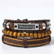 Macro shot of multilayer brown leather bracelets with wooden beads and engraved hope tag