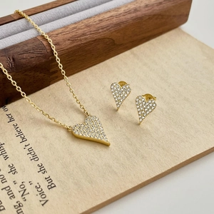 Golden S925 silver heart necklace and earrings set with sparkling zircon on a wood box