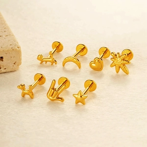 Golden titanium alloy ear stud set with star and heart shapes on a beige stone background