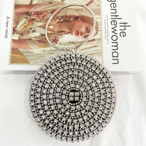 Chic silver rhinestone evening bag with a metal ring handle shown on a fashion magazine
