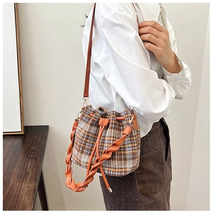 Close-up of retro plaid tweed bucket bag featuring leather drawstring and woven handle