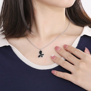 Detail of model wearing a butterfly necklace with black shell pendant on a silver chain