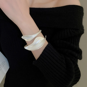 Detailed view of a matte silver leaf-shaped open cuff bracelet worn on a wrist