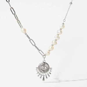 Détail d'un collier en perles argentées avec un pendentif œil unique motif soleil