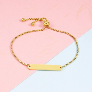 Close-up of polished gold bar bracelet with adjustable box chain on pastel background