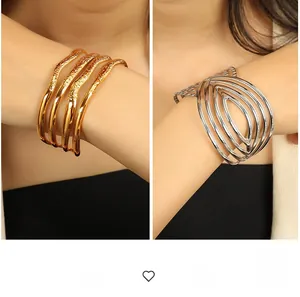 Macro detail of 18K gold and silver plated chunky layered cuff bracelets with polished finish