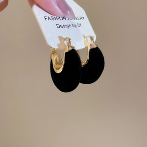 Detailed macro view of U-shaped gold earrings with black velvet teardrop inlays