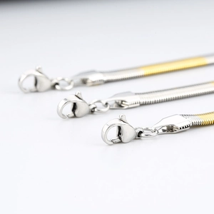 Detail of flat snake chains with lobster clasps in silver and two-tone gold finishes