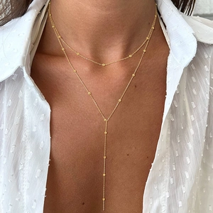 Detailed view of layered gold Y-necklace with small beads on an elegant model