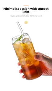 Detail eines Glasbechers in Dosenform mit Trinkhalm und Eiskaffee mit grünen Blättern