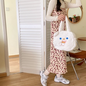 Detailed close-up of white plush tote bag with cute cartoon embroidery and soft texture