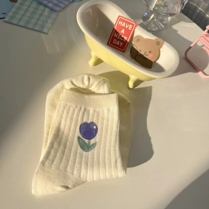 Detail showing beige mid-calf cotton socks with purple tulip embroidery and bear card