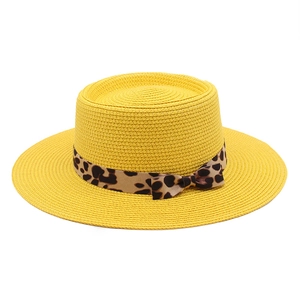 Detail of yellow handmade straw boater hat featuring a leopard print ribbon bow