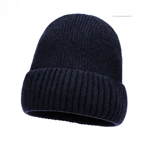 Detail of navy blue knitted beanie featuring a brown leather patch and ribbed texture
