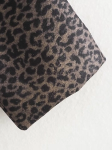 Close-up of animal leopard print coat fabric showing soft wool-like texture and pattern