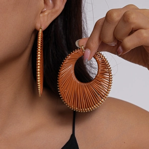 Close-up of bohemian woven geometric hoop earrings with brown texture and gold beads