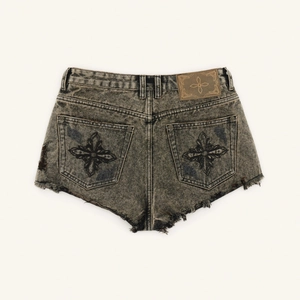 Detailansicht der Vintage-Denim-Shorts mit Acid-Wash-Effekt und Kreuzstickerei auf der Tasche