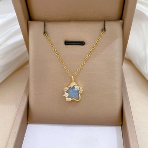 Macro detail of gold star pendant necklace with deep blue stone and sparkling crystals