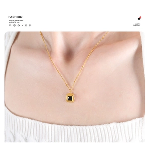 Detail of vintage gold square black stone pendant necklace on a white knit collar