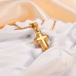 Close-up of golden cross pendant with 3D relief texture on luxury satin fabric