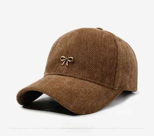 Detail view of brown corduroy baseball cap with herringbone texture and gold bow
