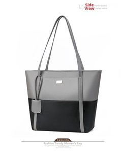 Detail of grey and black patchwork tote bag showing PU leather texture and gold metal plaque