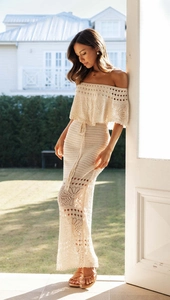 Dettaglio dell'abito lungo in maglia beige a uncinetto con spalle scoperte e trama intrecciata
