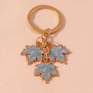 Close-up of golden ginkgo leaf pendants with grey marble enamel finish on a pink base