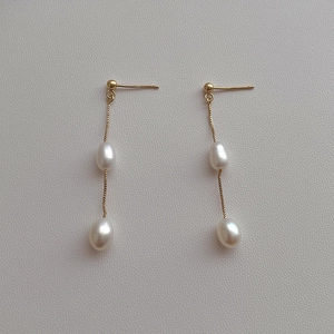 Detail of long tassel earrings with white freshwater pearls and fine gold chain