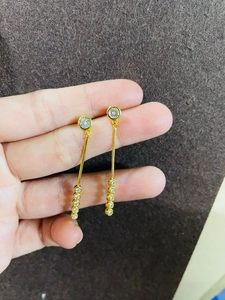 Gros plan de boucles d'oreilles pendantes plaquées or avec cristaux ronds tenus par mannequin