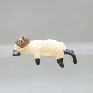 Close-up of a cute Siamese cat resin ornament in a lying pose for desk edge decoration