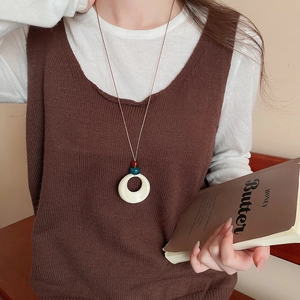 Detail of hollow round resin pendant on long sweater chain with retro ethnic style