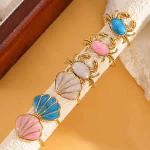 Macro view of gold-plated ocean rings featuring crab and shell charms with colorful enamel