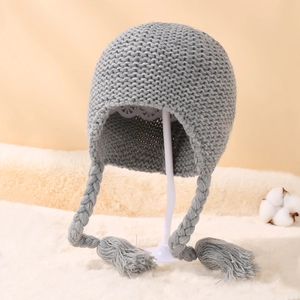 Detailed close-up of grey cable-knit baby bonnet with tassels and soft ear protection