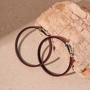 Detail view of large round retro earrings with red-brown faux leather on warm stone